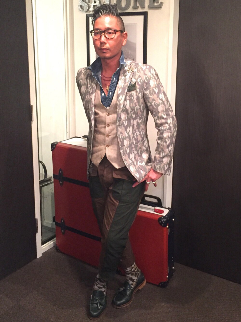 グリーン系のテーラードジャケット、ベージュ系のベスト、ブラウン系のカーゴパンツを着用したメンズの春コーディネートの1枚目の写真