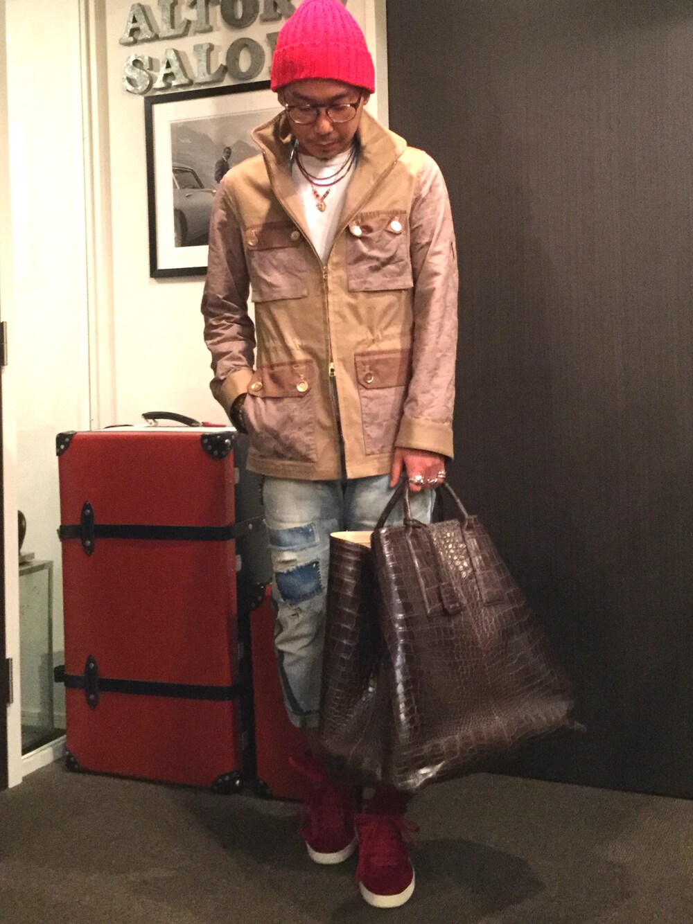 ベージュ系のミリタリージャケット、ブラウン系のトートバッグ、レッド系のスニーカーを着用したメンズの夏コーディネートの1枚目の写真