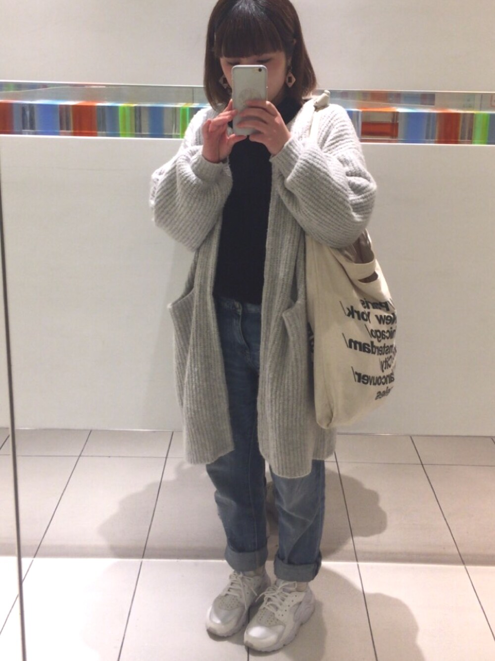 グレー系のカーディガン/ボレロ、ホワイト系のトートバッグ、ブラック系のニット/セーターを着用したレディースの秋コーディネートの1枚目の写真