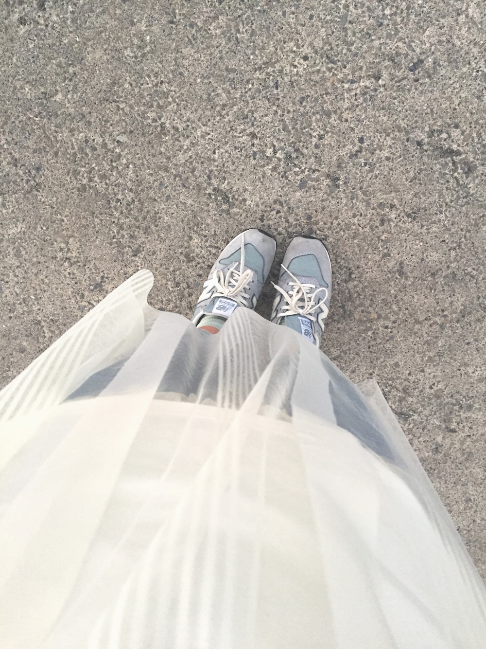 ブルー系のスニーカー、ホワイト系のワンピース、ブルー系のデニムパンツを着用したレディースの春コーディネートの1枚目の写真