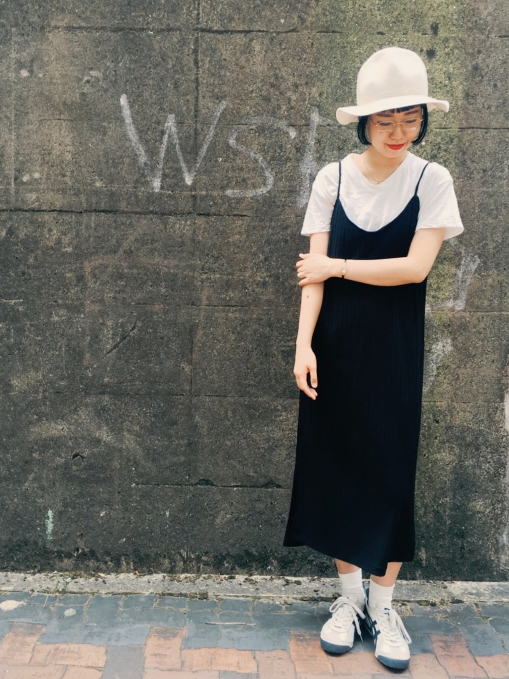 ブラック系のワンピース、ベージュ系のスニーカー、ホワイト系のハットを着用したレディースの夏コーディネートの1枚目の写真