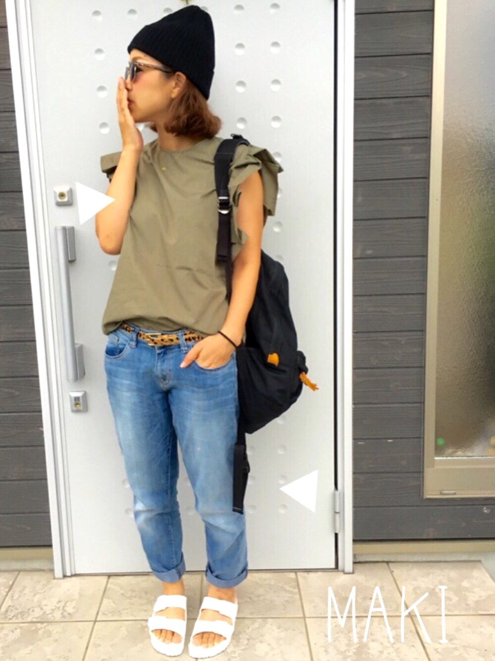 グリーン系のトップス、ブラック系のバックパック/リュック、ホワイト系のサンダルを着用したレディースの夏コーディネートの1枚目の写真