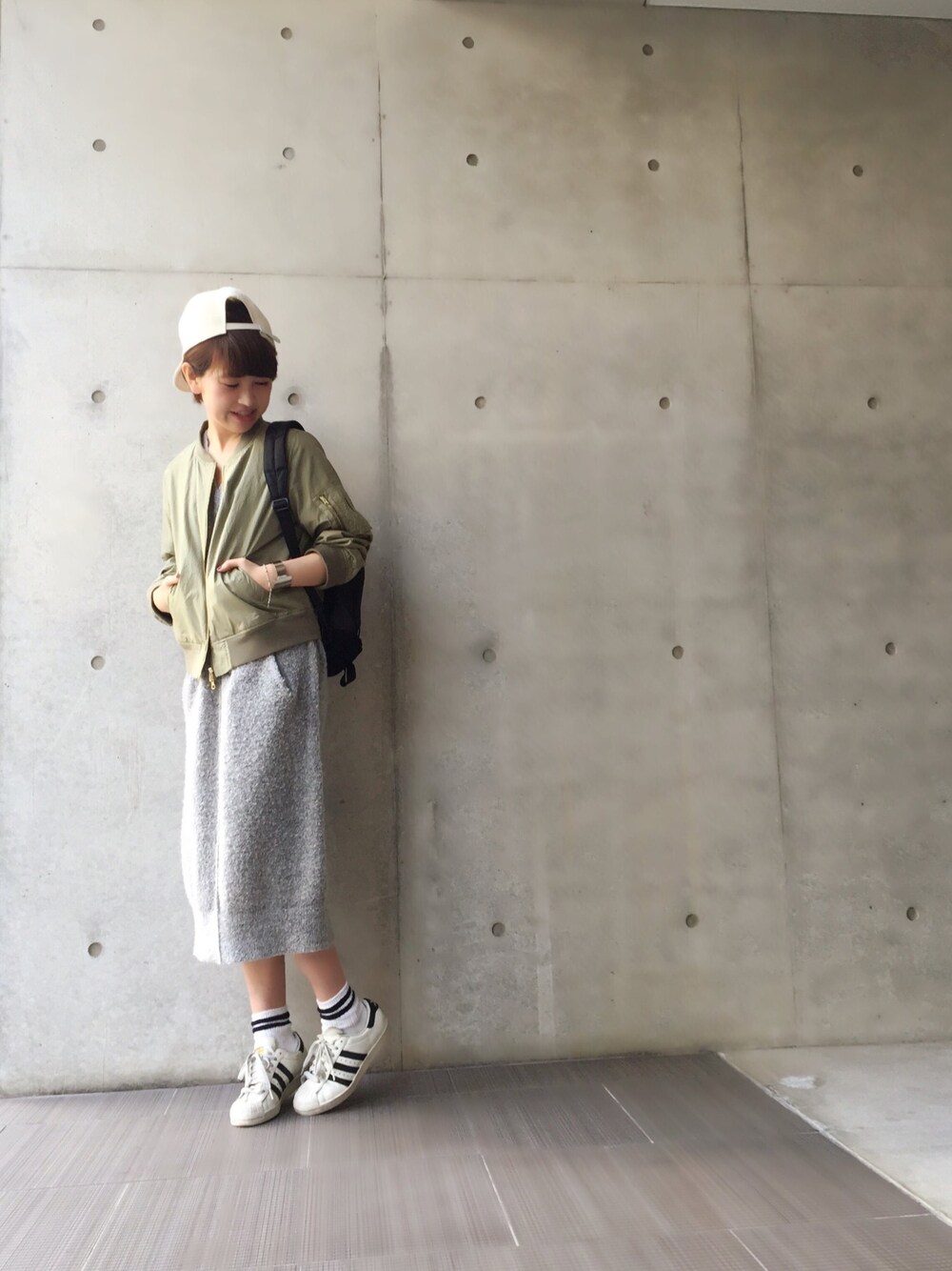 グリーン系のミリタリージャケット、グレー系のワンピース、ホワイト系のスニーカーを着用したレディースの冬コーディネートの1枚目の写真