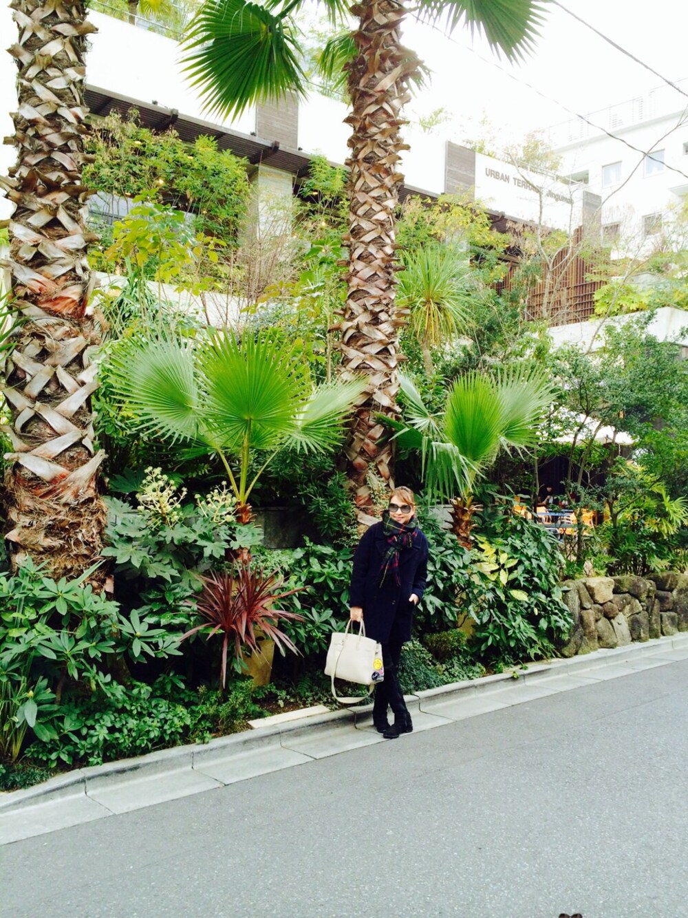 ブルー系のチェスターコート、ブラック系のスラックス、ブラック系のブーツを着用したレディースの冬コーディネートの1枚目の写真