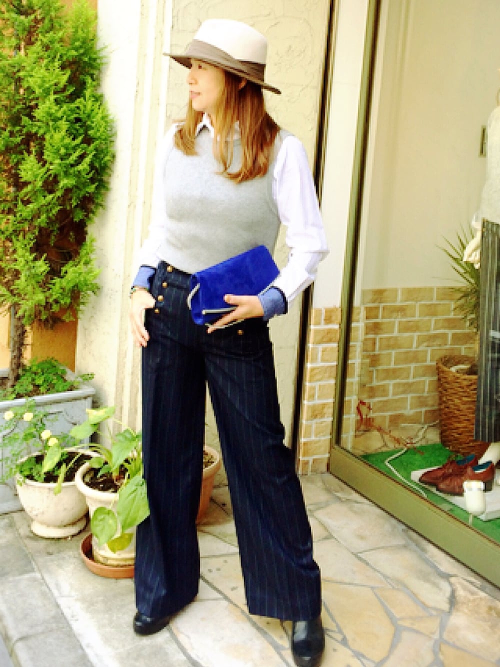 ホワイト系のシャツ/ブラウス、ブルー系のクラッチバッグ、ブルー系のスラックスを着用したレディースの秋コーディネートの1枚目の写真