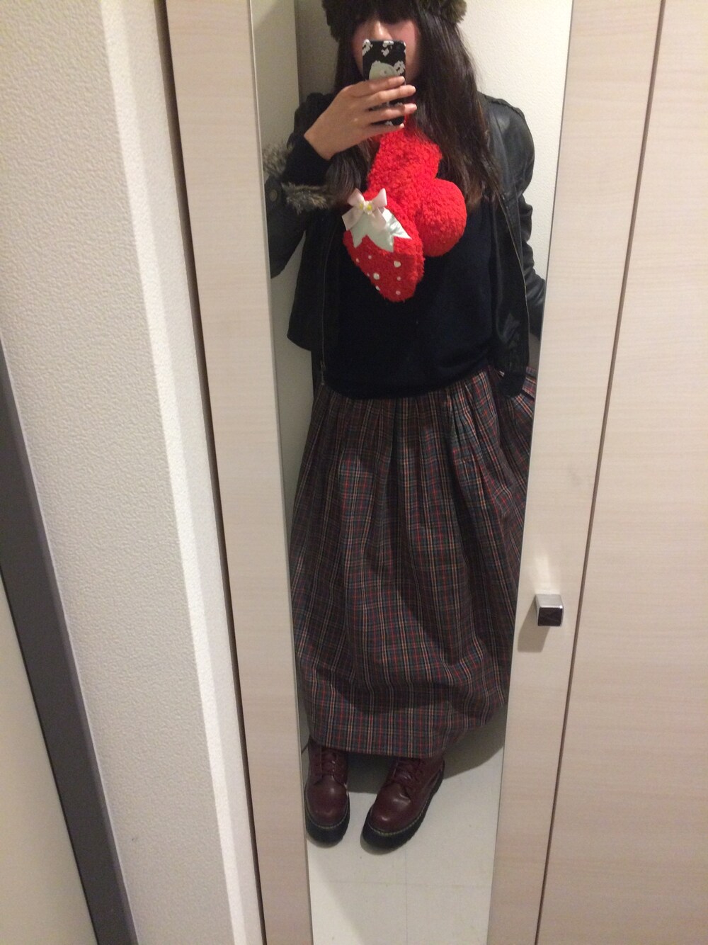 レッド系のブーツ、グリーン系のスカート、レッド系のマフラーを着用したレディースの冬コーディネートの1枚目の写真