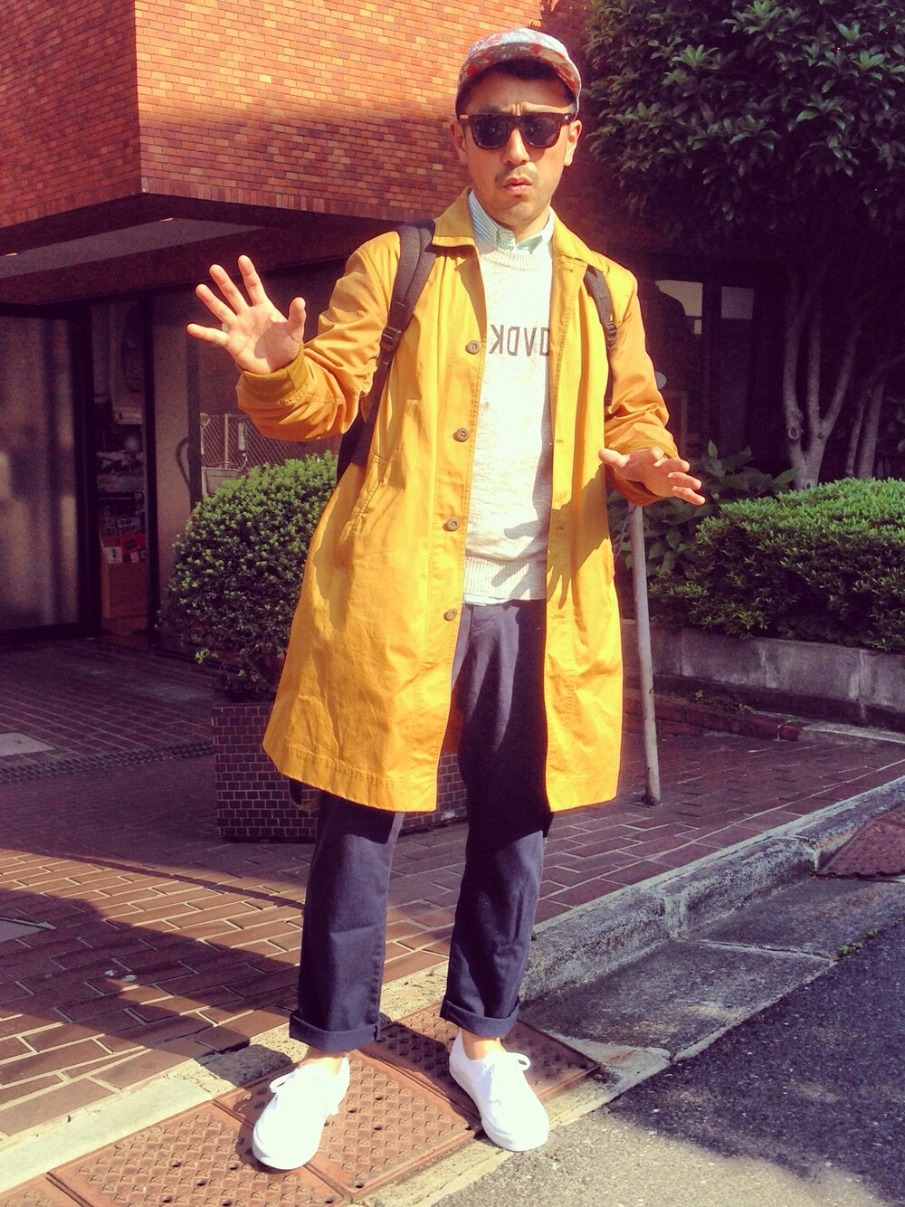 ブルー系のチノパンツ、イエロー系のステンカラーコート、グレー系のニット/セーターを着用したメンズの春コーディネートの1枚目の写真