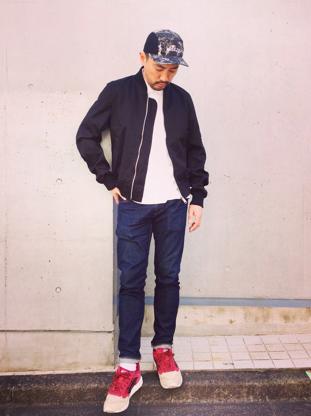 ブラック系のミリタリージャケット、ブルー系のデニムパンツ、ブラック系のキャップを着用したメンズの春コーディネートの1枚目の写真