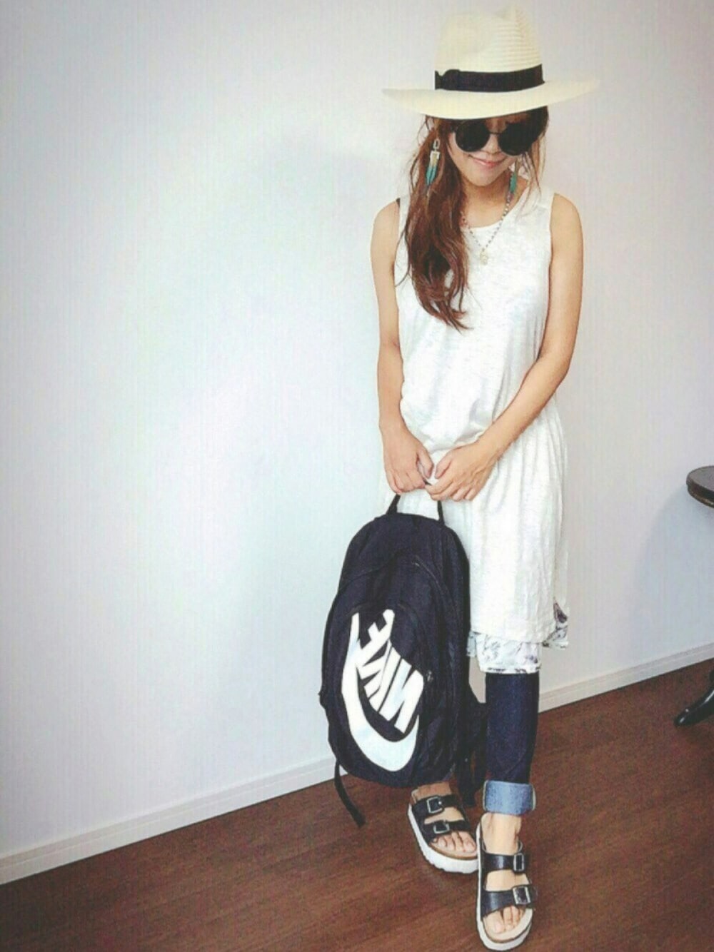 ホワイト系のワンピース、ブルー系のデニムパンツ、ブラック系のサンダルを着用したレディースの夏コーディネートの1枚目の写真