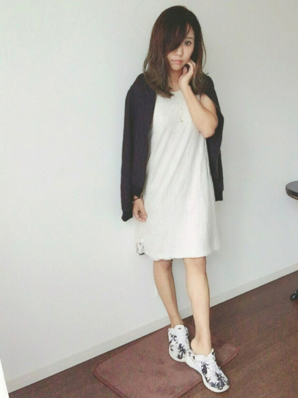 ブラック系のブルゾン、ホワイト系のワンピース、ホワイト系のスニーカーを着用したレディースの秋コーディネートの1枚目の写真