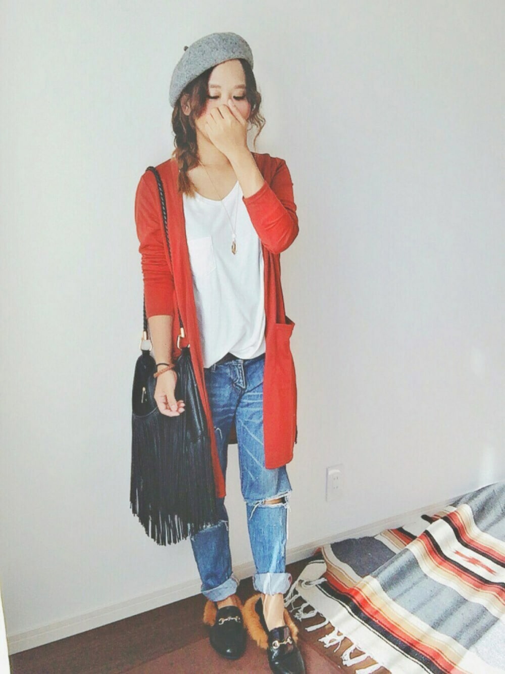 ブラウン系のカーディガン/ボレロ、ブラック系のショルダーバッグ、ブルー系のデニムパンツを着用したレディースの秋コーディネートの1枚目の写真