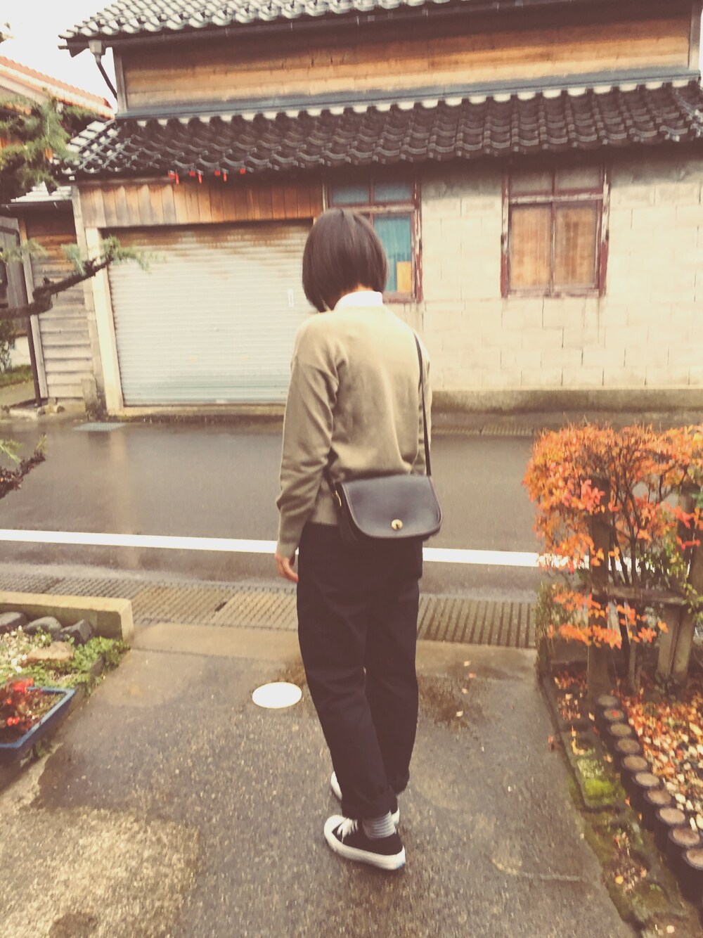 グリーン系のニット/セーター、ブラック系のショルダーバッグ、ブルー系のチノパンツを着用したレディースの秋コーディネートの1枚目の写真