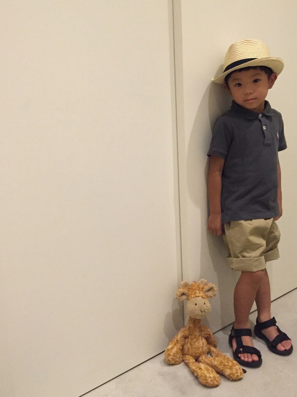 グレー系のポロシャツ、ベージュ系のその他パンツ、ベージュ系の帽子を着用したキッズの夏コーディネートの1枚目の写真