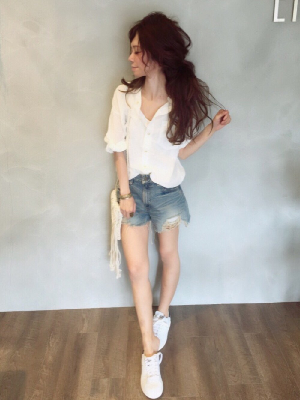 ホワイト系のショルダーバッグ、ブラック系のスニーカー、ブルー系のデニムパンツを着用したレディースの夏コーディネートの1枚目の写真