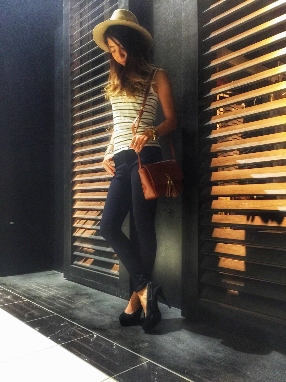 ホワイト系のタンクトップ、ブラウン系のショルダーバッグ、ブルー系のパンツを着用したレディースの夏コーディネートの1枚目の写真