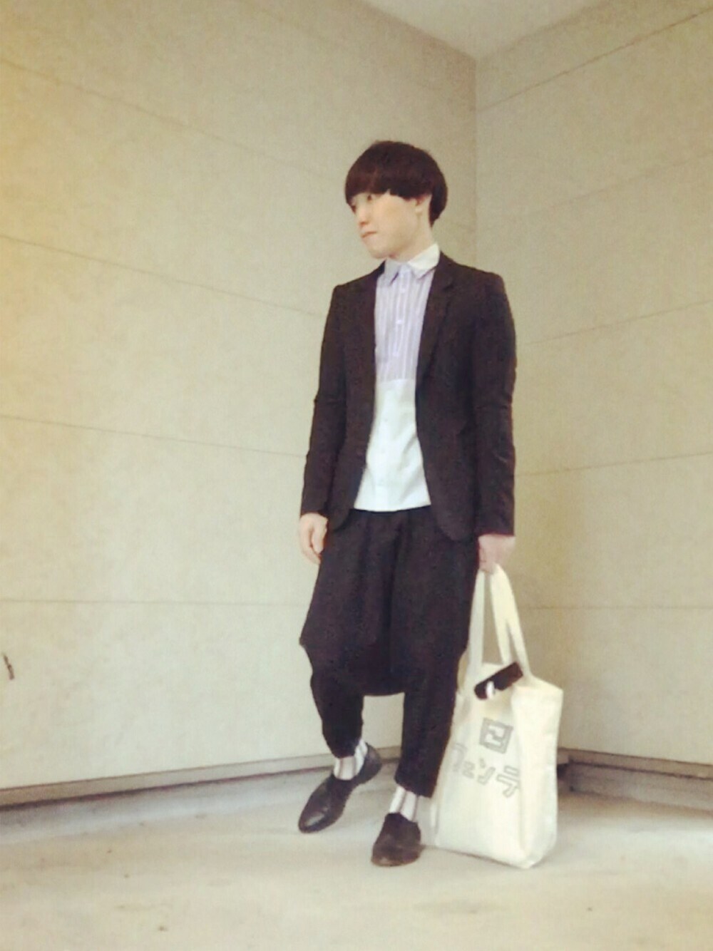 ブラック系のその他パンツ、ブラック系のテーラードジャケット、ベージュ系のトートバッグを着用したメンズの春コーディネートの1枚目の写真