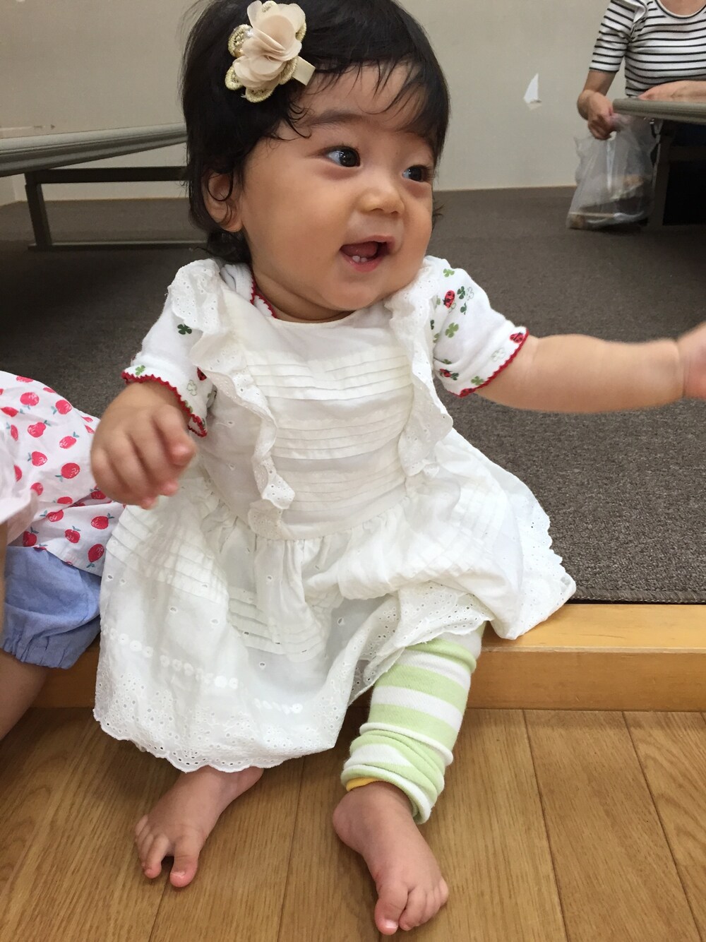 ホワイト系のワンピース、グリーン系のレッグウォーマー、レッド系のロンパースを着用したキッズの秋コーディネートの1枚目の写真