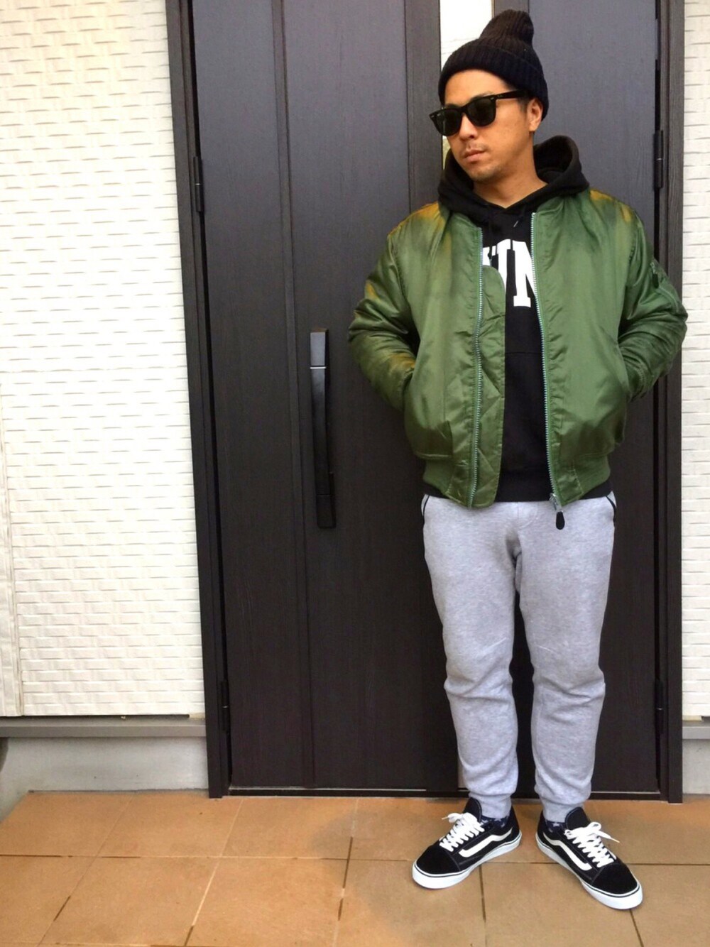 グリーン系のミリタリージャケット、ブラック系のパーカー、グレー系のその他パンツを着用したメンズの秋コーディネートの1枚目の写真