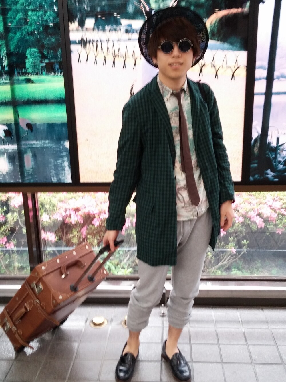 ブルー系のモカシン/デッキシューズ、グリーン系のステンカラーコート、ブラック系のハットを着用したメンズの夏コーディネートの1枚目の写真