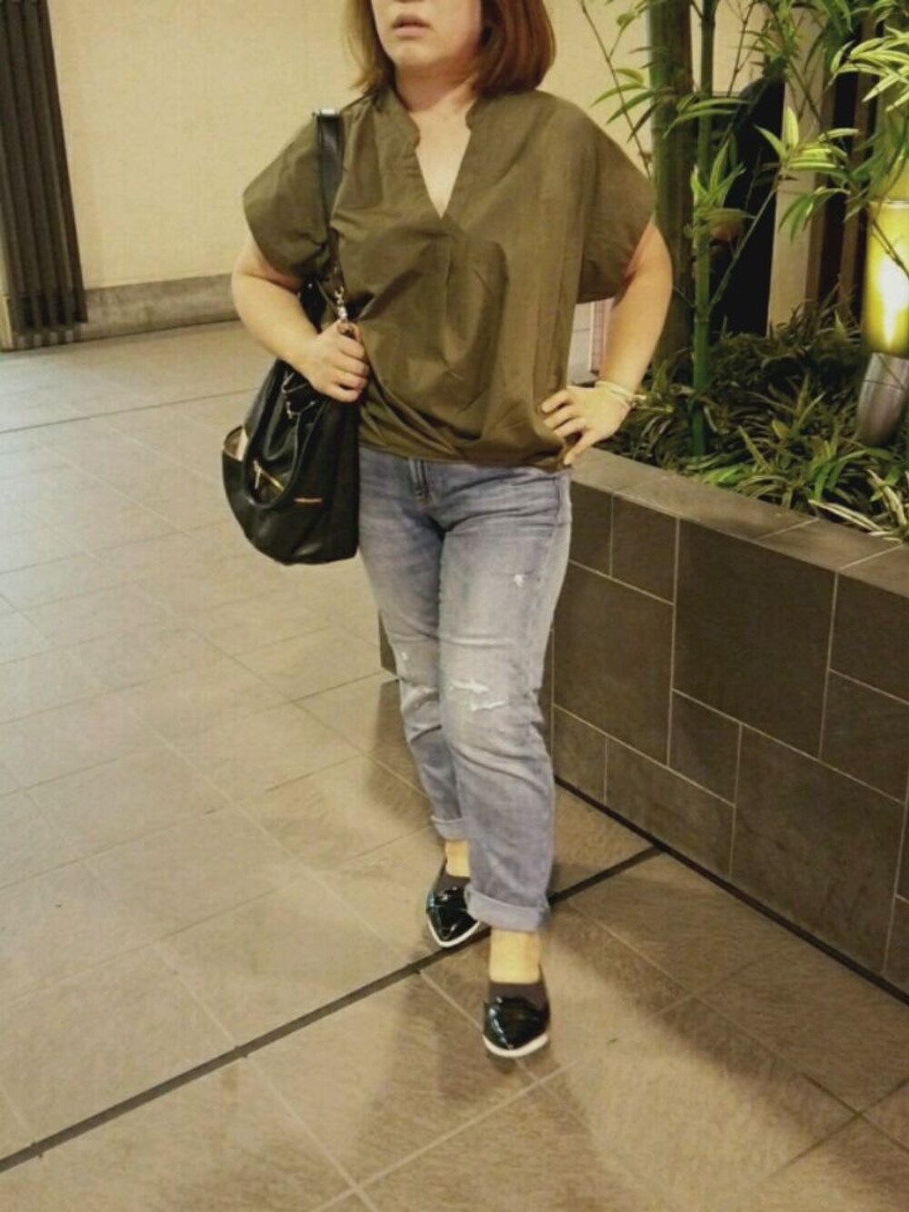 ブラック系のパンプス、ブラック系のハンドバッグ、ブルー系のデニムパンツを着用したレディースの夏コーディネートの1枚目の写真