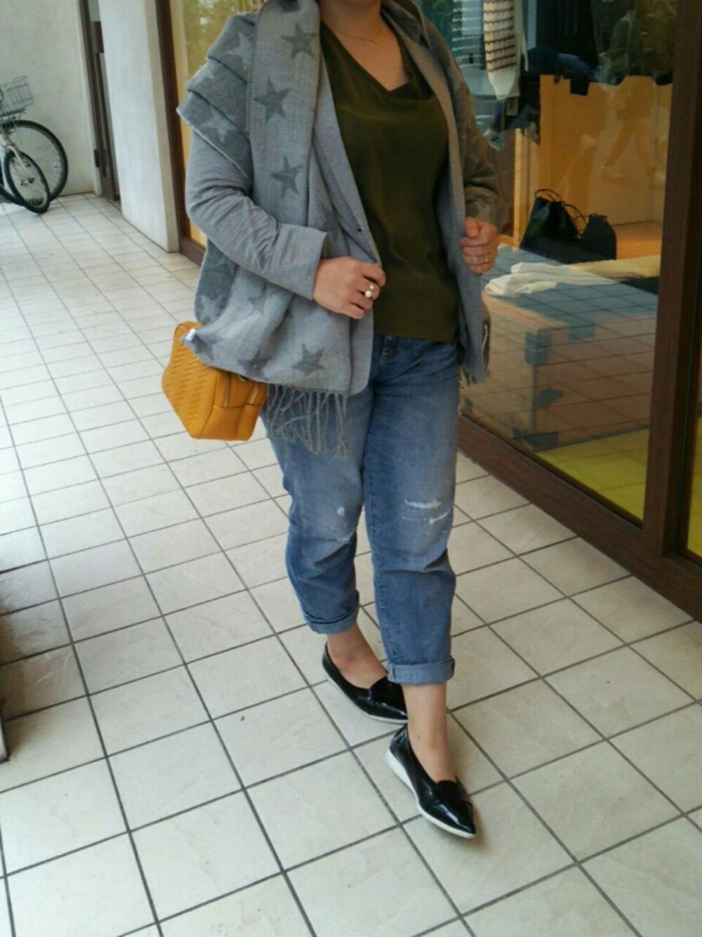 イエロー系のショルダーバッグ、ブルー系のデニムパンツ、グリーン系のシャツ/ブラウスを着用したレディースの秋コーディネートの1枚目の写真