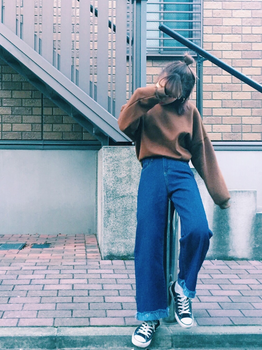 ブルー系のデニムパンツ、ブラウン系のスウェット、ホワイト系のスニーカーを着用したレディースの冬コーディネートの1枚目の写真