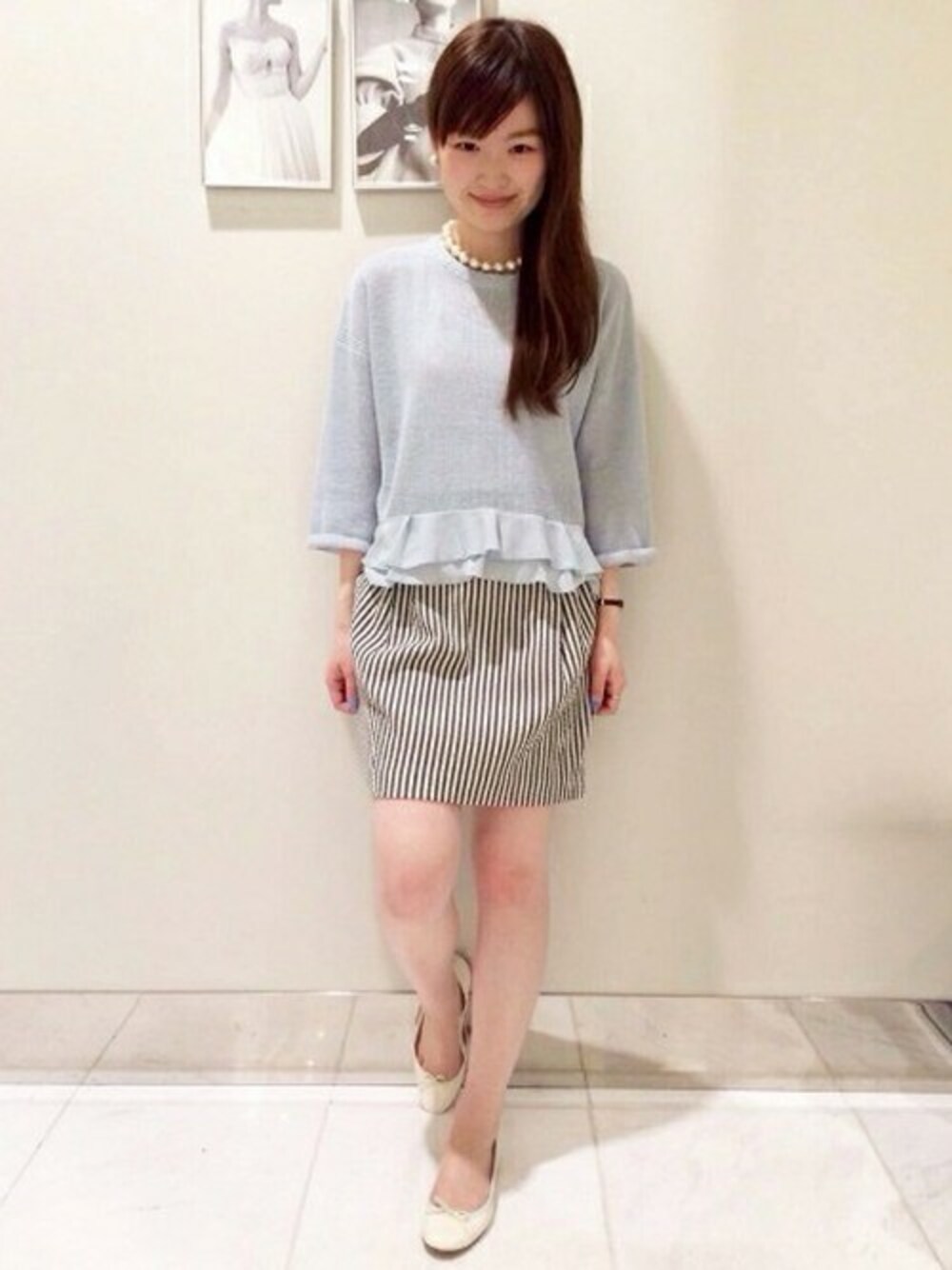 グリーン系のニット/セーター、ブラック系のスカート、ホワイト系のバレエシューズを着用したレディースの春コーディネートの1枚目の写真