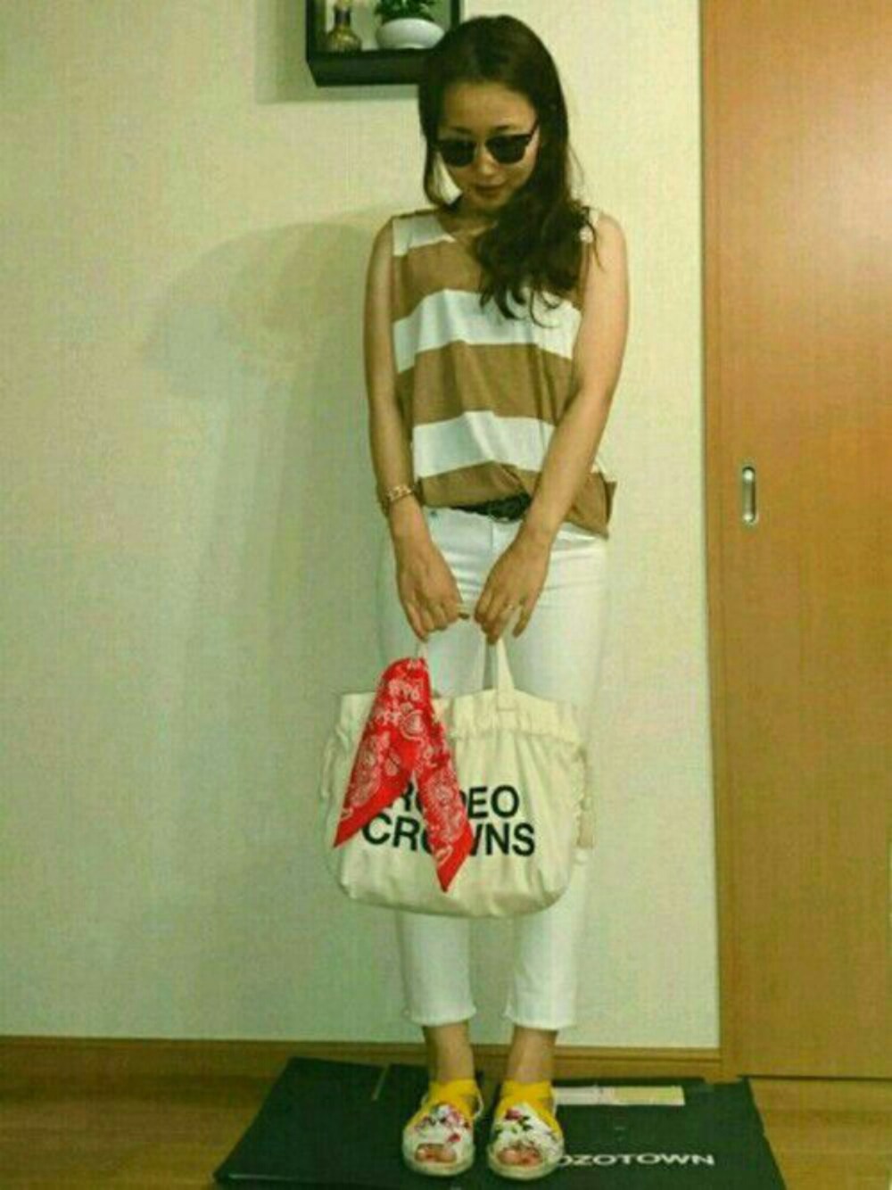 ブラウン系のタンクトップ、ベージュ系のトートバッグ、その他のサンダルを着用したレディースの夏コーディネートの1枚目の写真