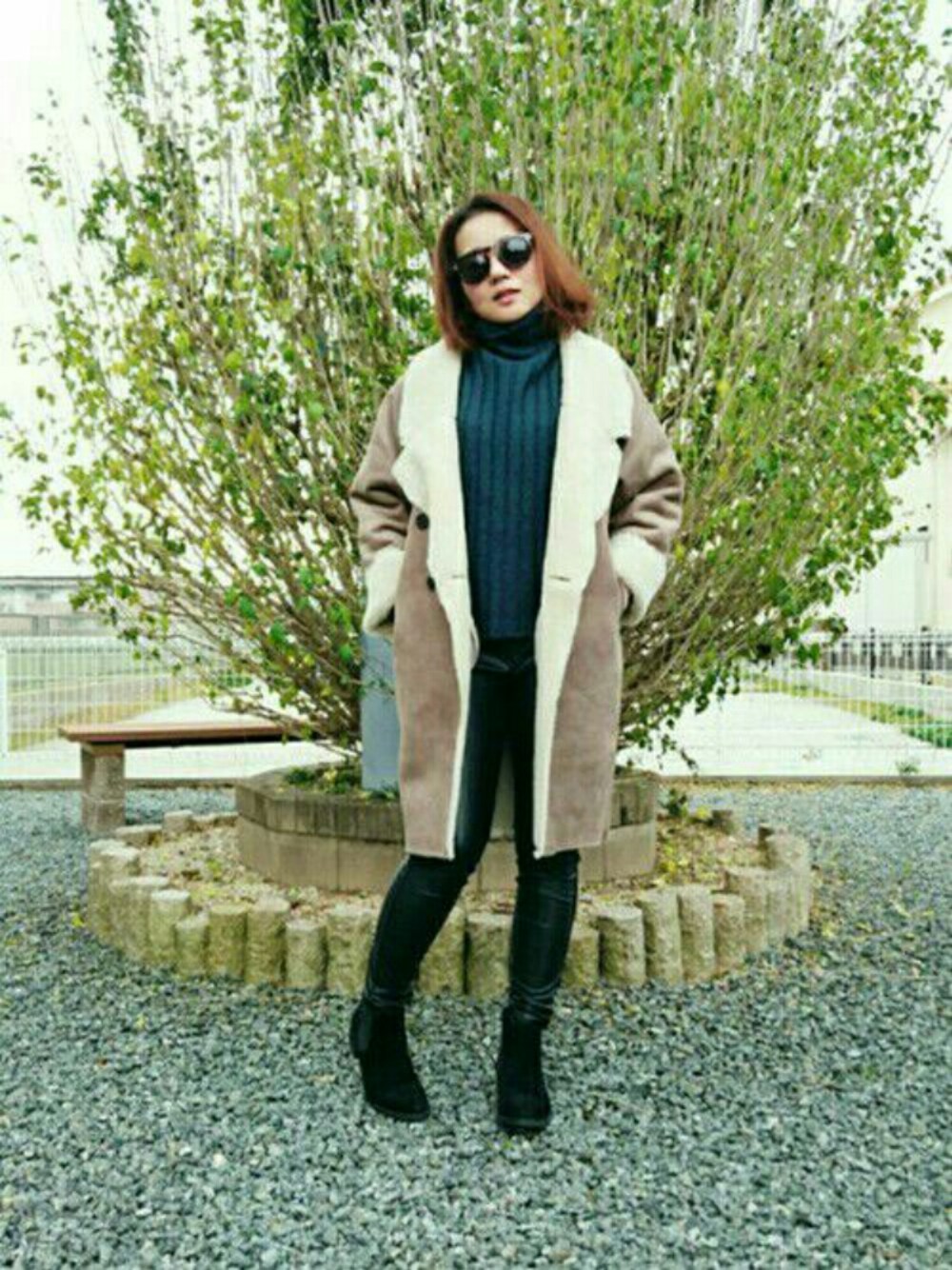 グリーン系のニット/セーター、ベージュ系のムートンコート、ブラック系のパンツを着用したレディースの冬コーディネートの1枚目の写真