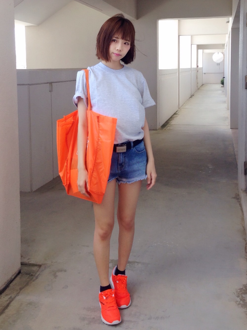 オレンジ系のスニーカー、ブルー系のデニムパンツ、グレー系のTシャツ/カットソーを着用したレディースの夏コーディネートの1枚目の写真