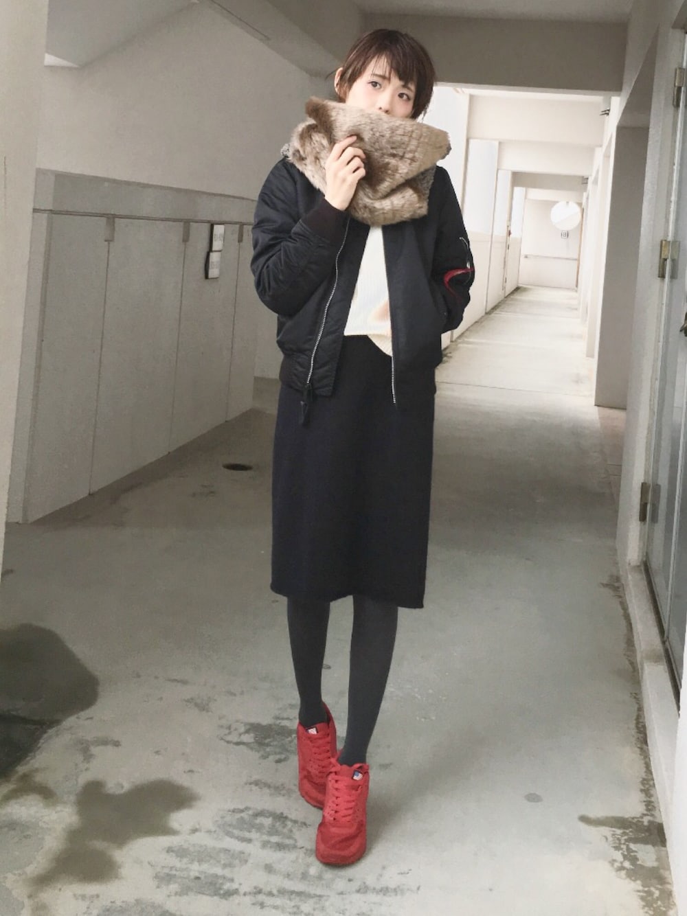 ブラック系のスカート、ホワイト系のニット/セーター、レッド系のスニーカーを着用したレディースの冬コーディネートの1枚目の写真