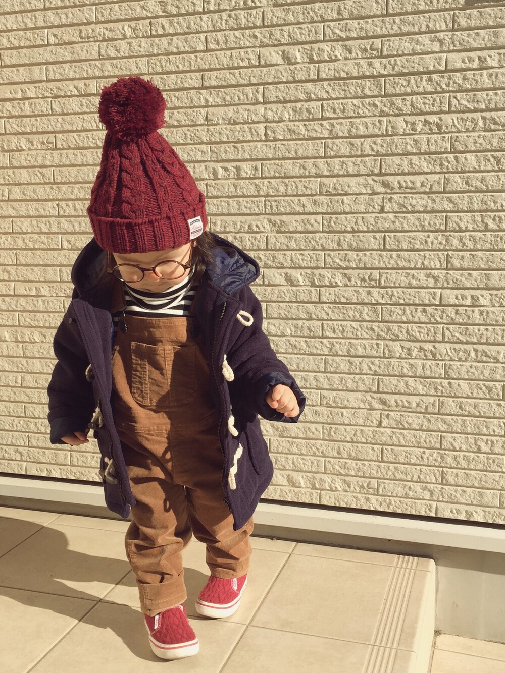 ブルー系のダッフルコート、イエロー系のサロペット/オーバーオール、ブラック系のトップスを着用したキッズの冬コーディネートの1枚目の写真