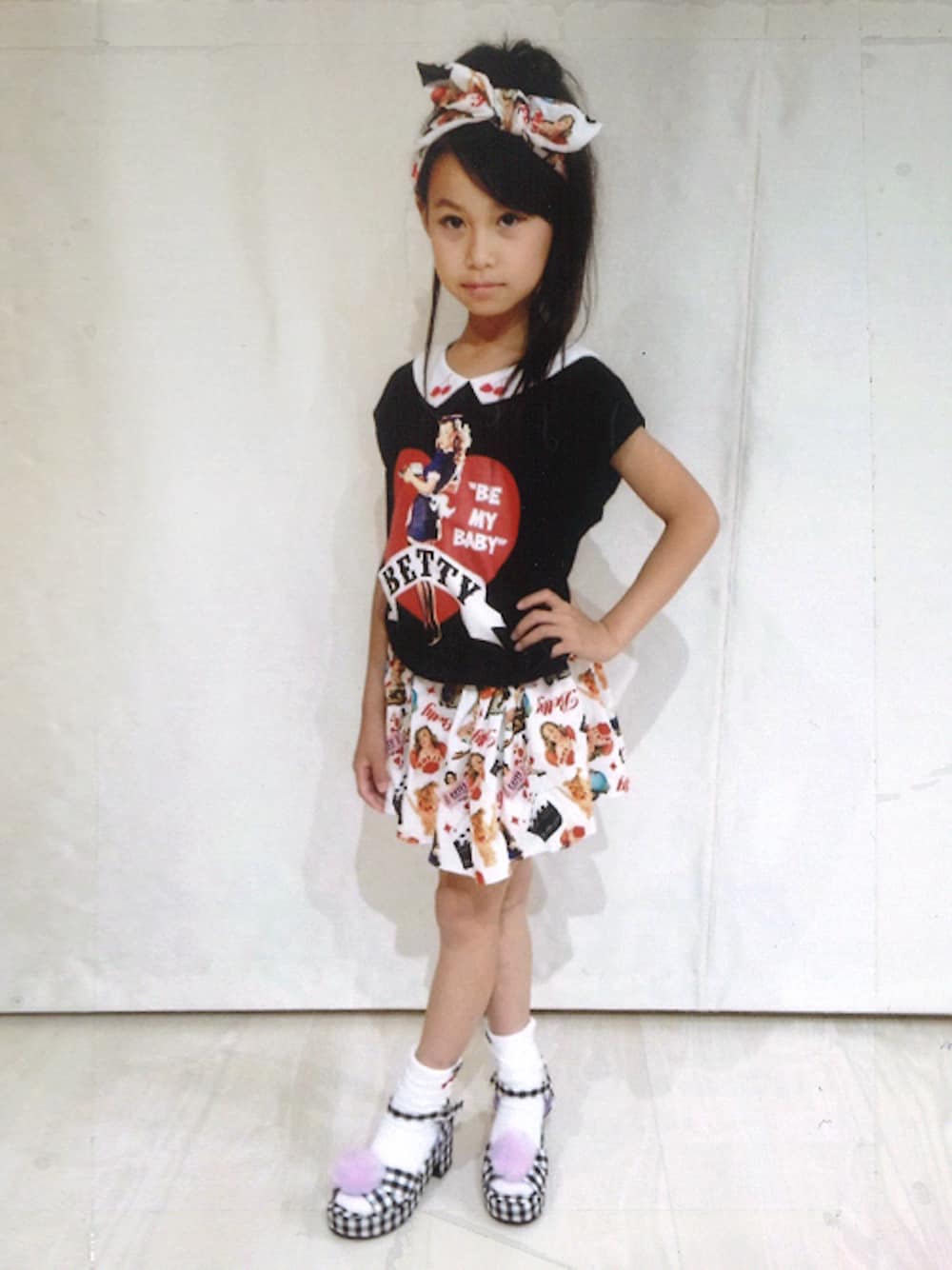 ブラック系のTシャツ/カットソー、ホワイト系のスカート、ブラック系のサンダルを着用したキッズの夏コーディネートの1枚目の写真