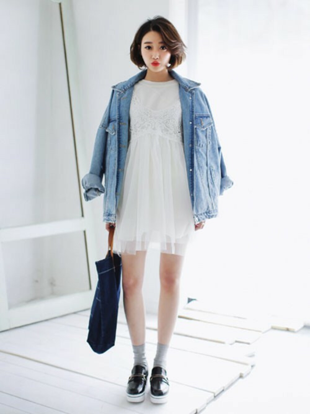 ブルー系のデニムジャケット、ホワイト系のワンピース、ブラック系のその他シューズを着用したレディースの春コーディネートの1枚目の写真