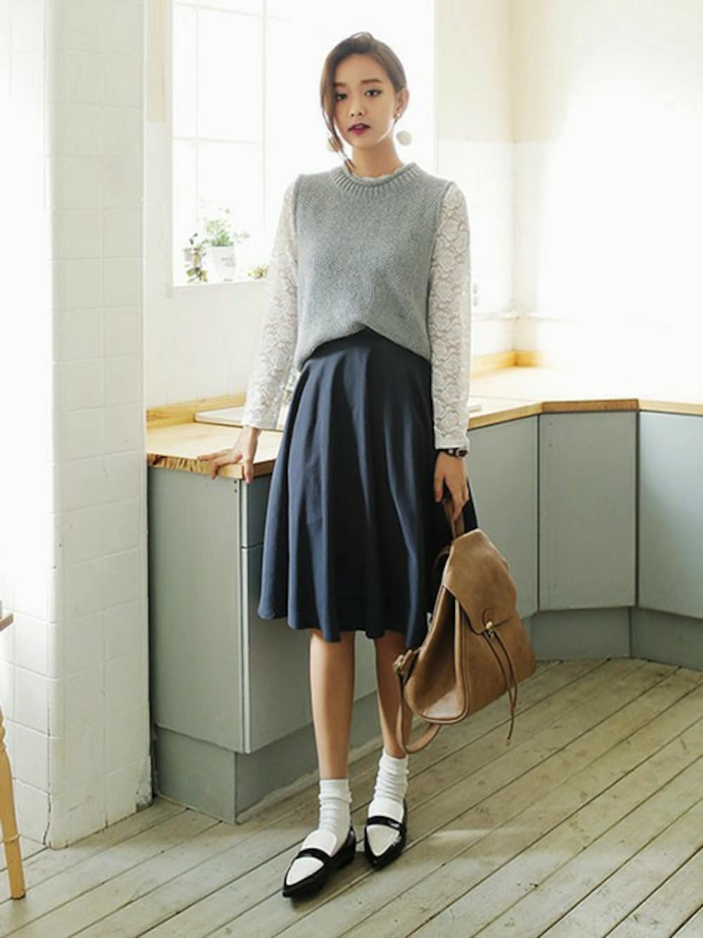 ブルー系のスカート、ベージュ系のバックパック/リュック、グレー系のベストを着用したレディースの秋コーディネートの1枚目の写真