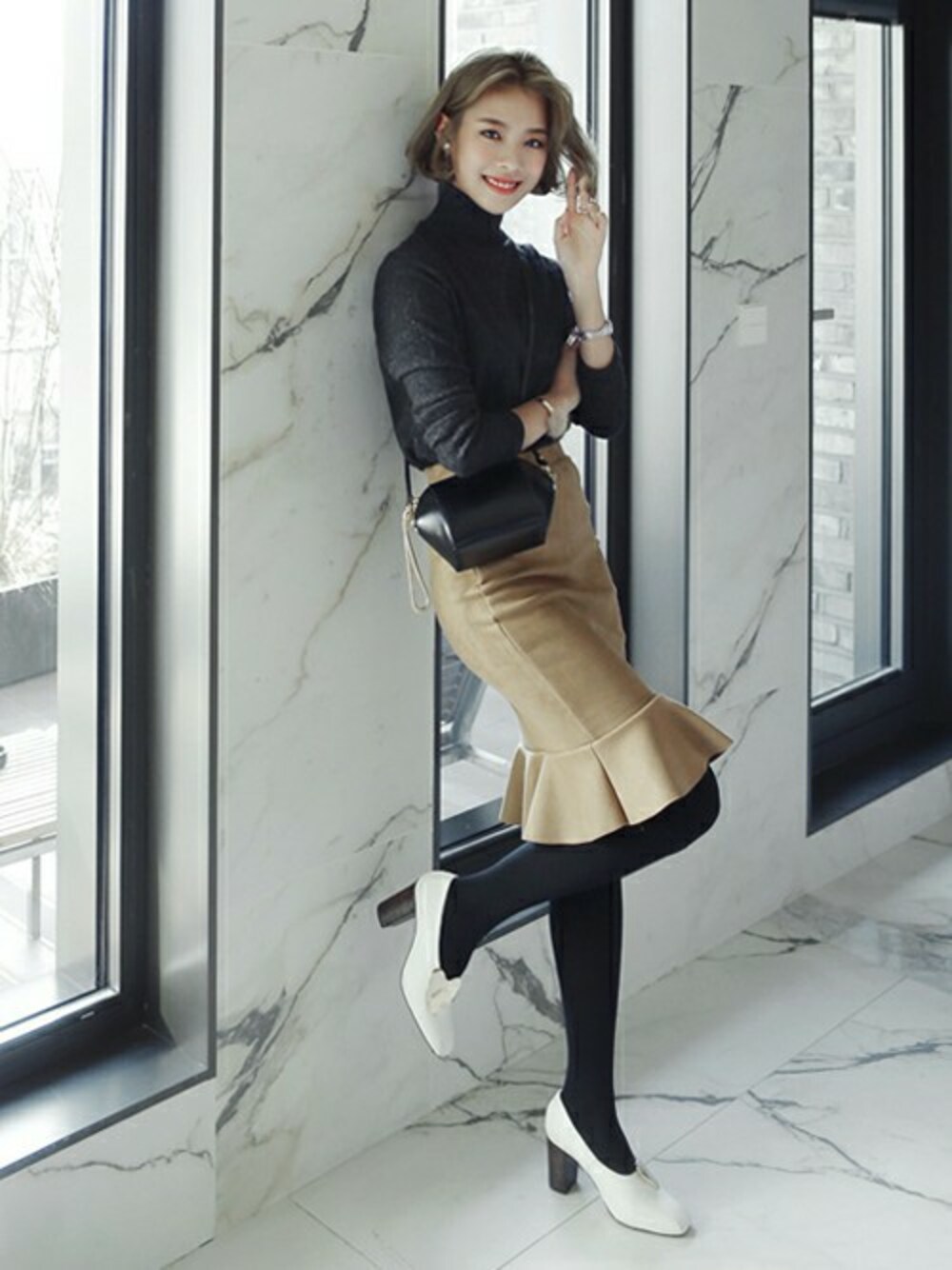 ベージュ系のスカート、グレー系のニット/セーターを着用したレディースの冬コーディネートの1枚目の写真