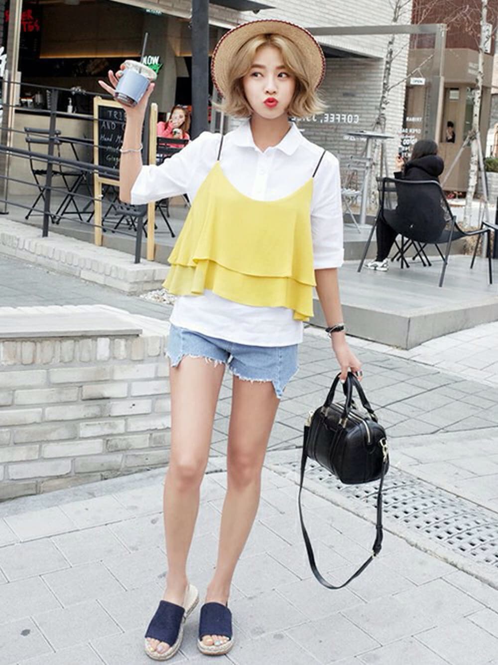 イエロー系のキャミソール、ブルー系のデニムパンツ、ブラック系のショルダーバッグを着用したレディースの春コーディネートの1枚目の写真