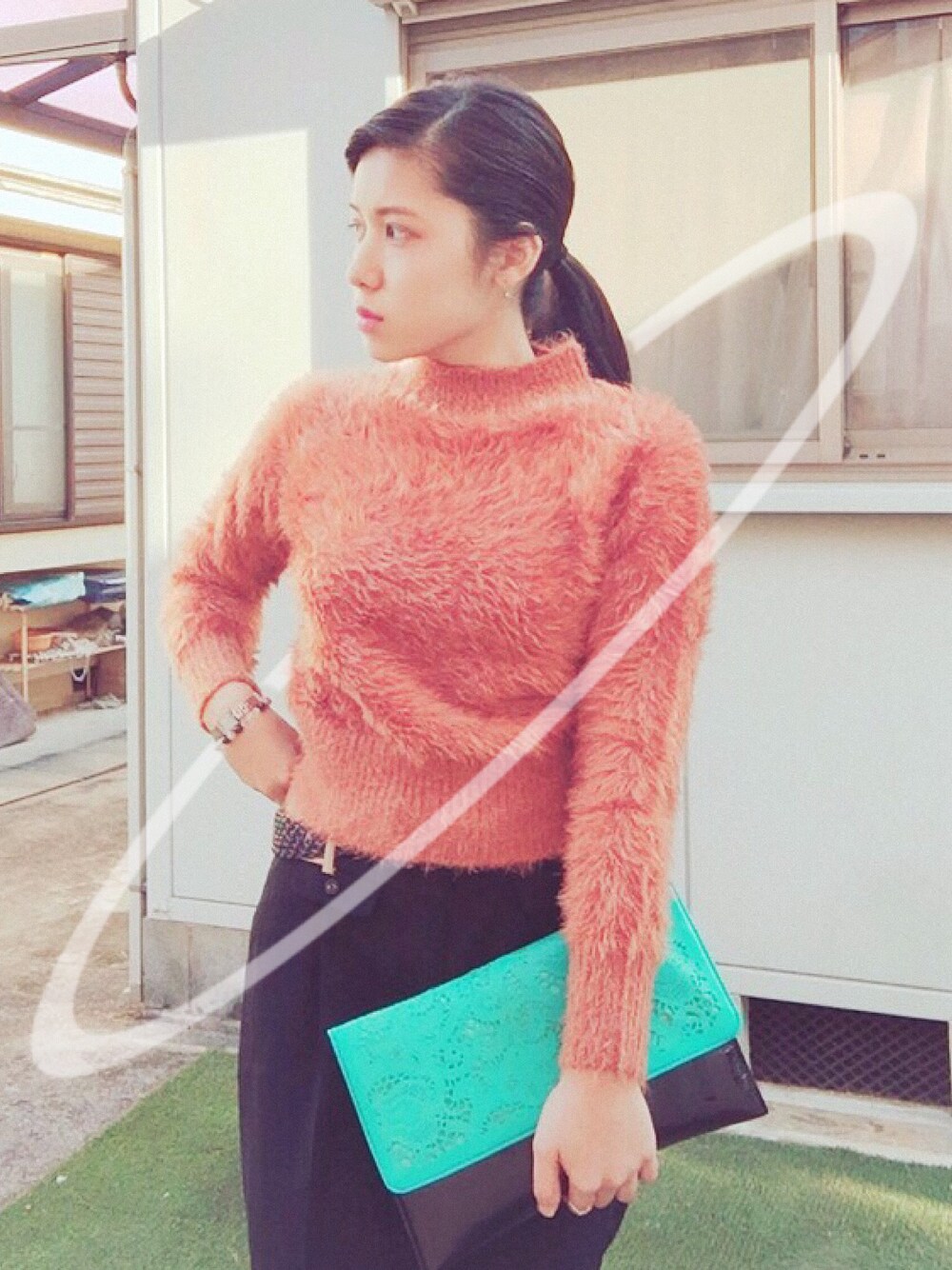 オレンジ系のニット/セーター、ブラック系のその他パンツ、その他のクラッチバッグを着用したレディースの冬コーディネートの1枚目の写真