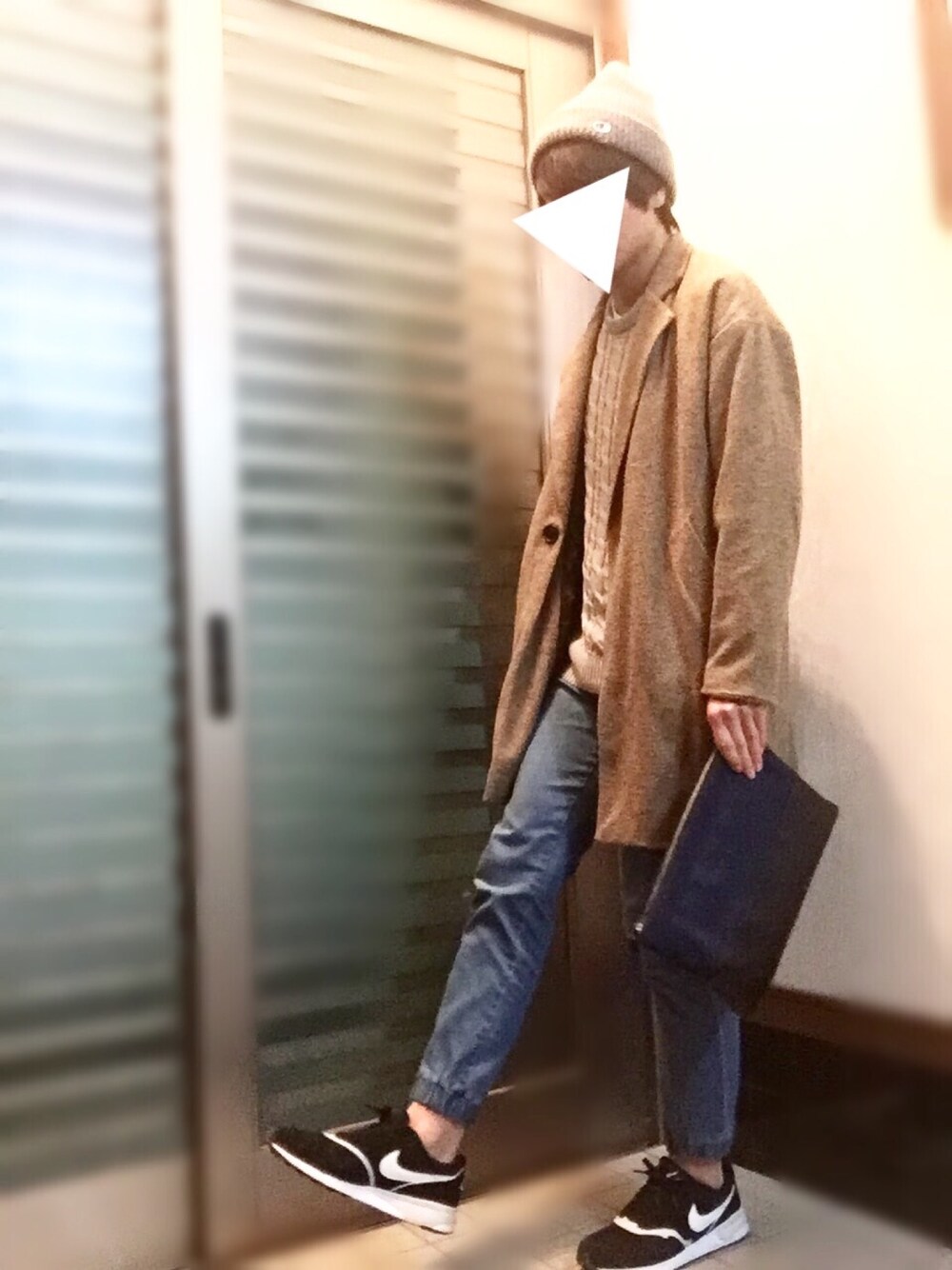 ベージュ系のチェスターコート、グレー系のニット/セーター、ブルー系のパンツを着用したメンズの春コーディネートの1枚目の写真