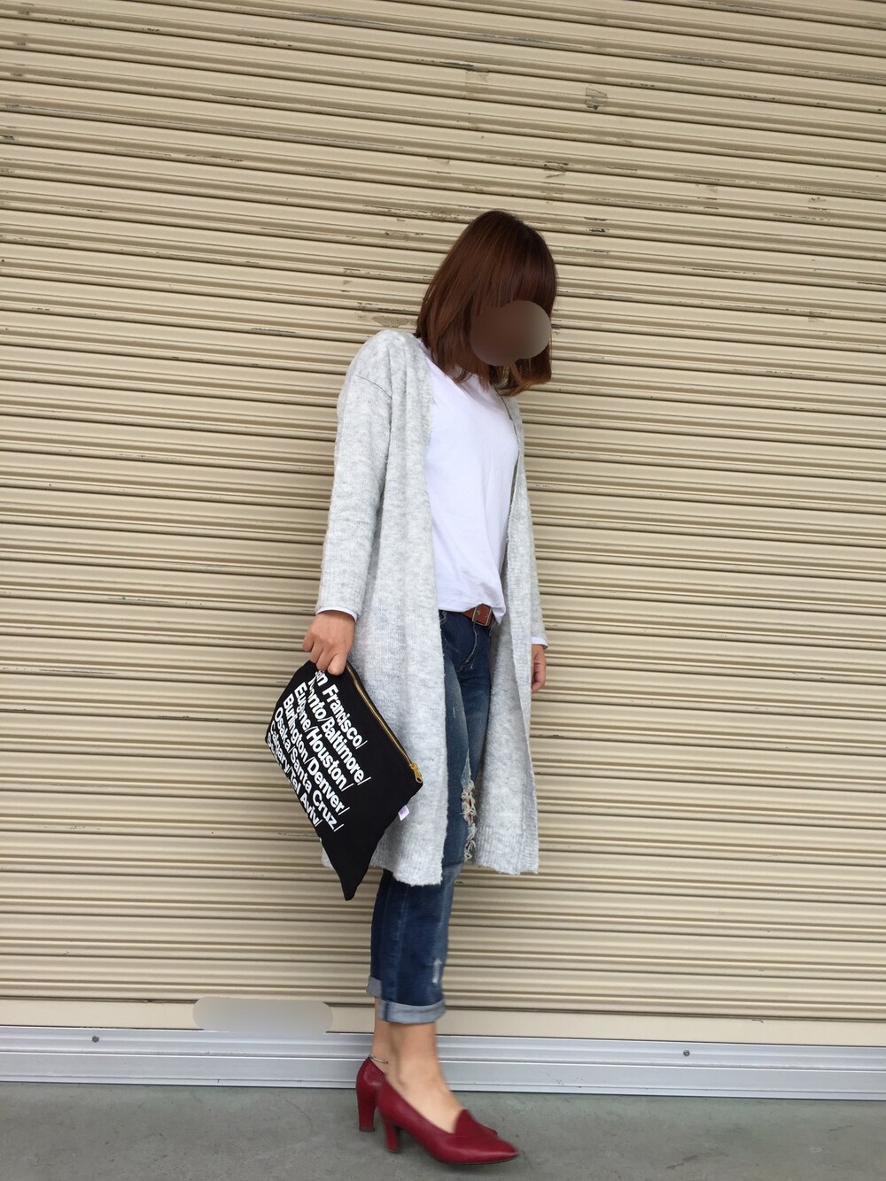 レッド系のパンプス、ブルー系のデニムパンツ、ブラック系のクラッチバッグを着用したレディースの秋コーディネートの1枚目の写真