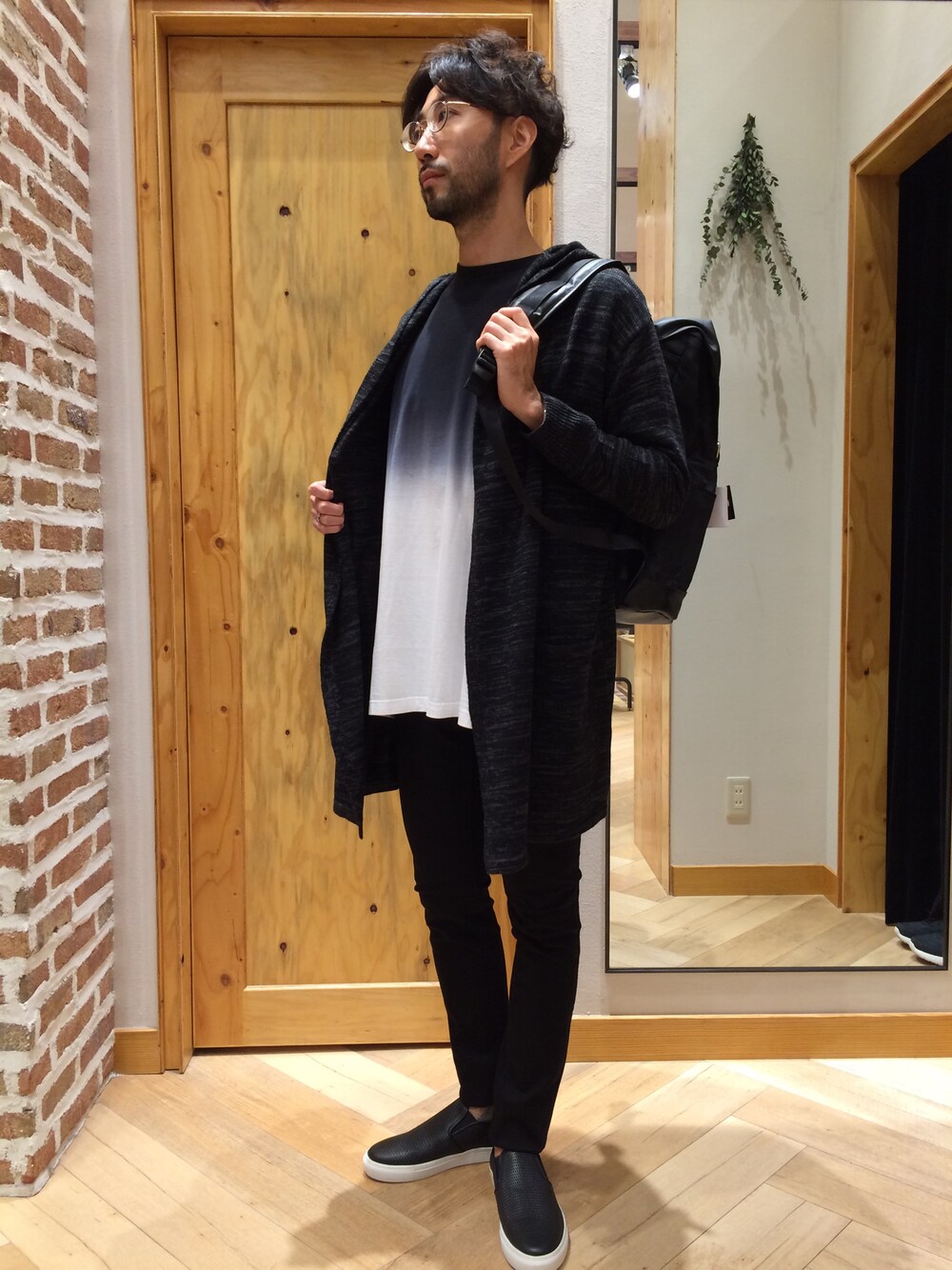 ブラック系のカーディガン/ボレロ、ブラック系のバックパック/リュック、ブラック系のTシャツ/カットソーを着用したメンズの秋コーディネートの1枚目の写真