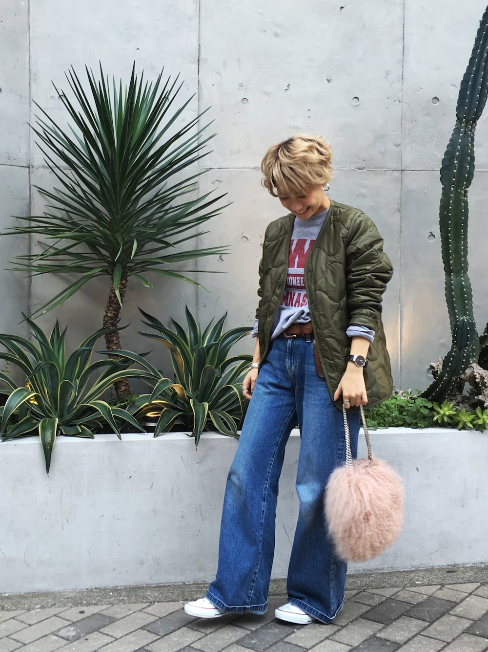 グリーン系のミリタリージャケット、グレー系のトップス、ブルー系のデニムパンツを着用したレディースの秋コーディネートの1枚目の写真