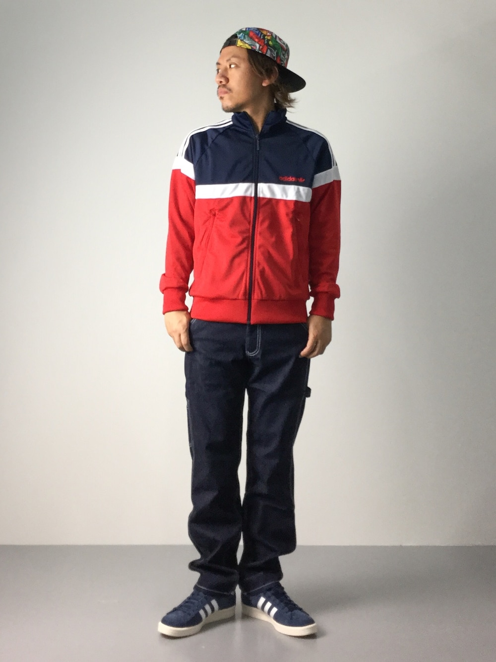 レッド系のジャージ、ブルー系のデニムパンツ、ブルー系のスニーカーを着用したメンズの夏コーディネートの1枚目の写真