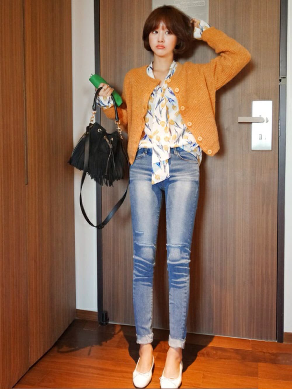 オレンジ系のカーディガン/ボレロ、イエロー系のシャツ/ブラウス、ブルー系のデニムパンツを着用したレディースの冬コーディネートの1枚目の写真