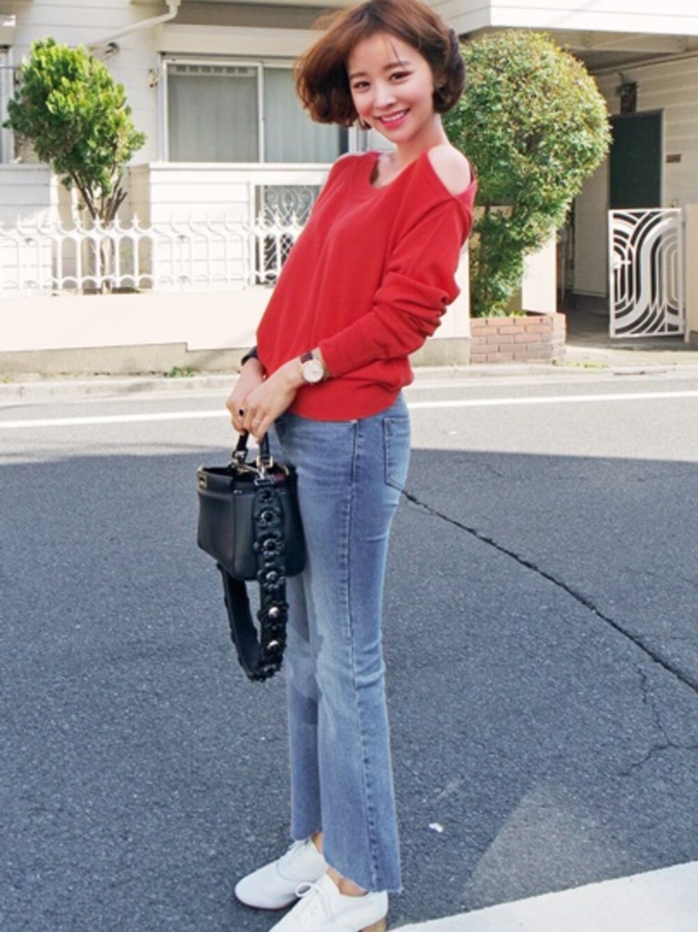 レッド系のニット/セーター、ブルー系のデニムパンツ、ホワイト系のスニーカーを着用したレディースの春コーディネートの1枚目の写真