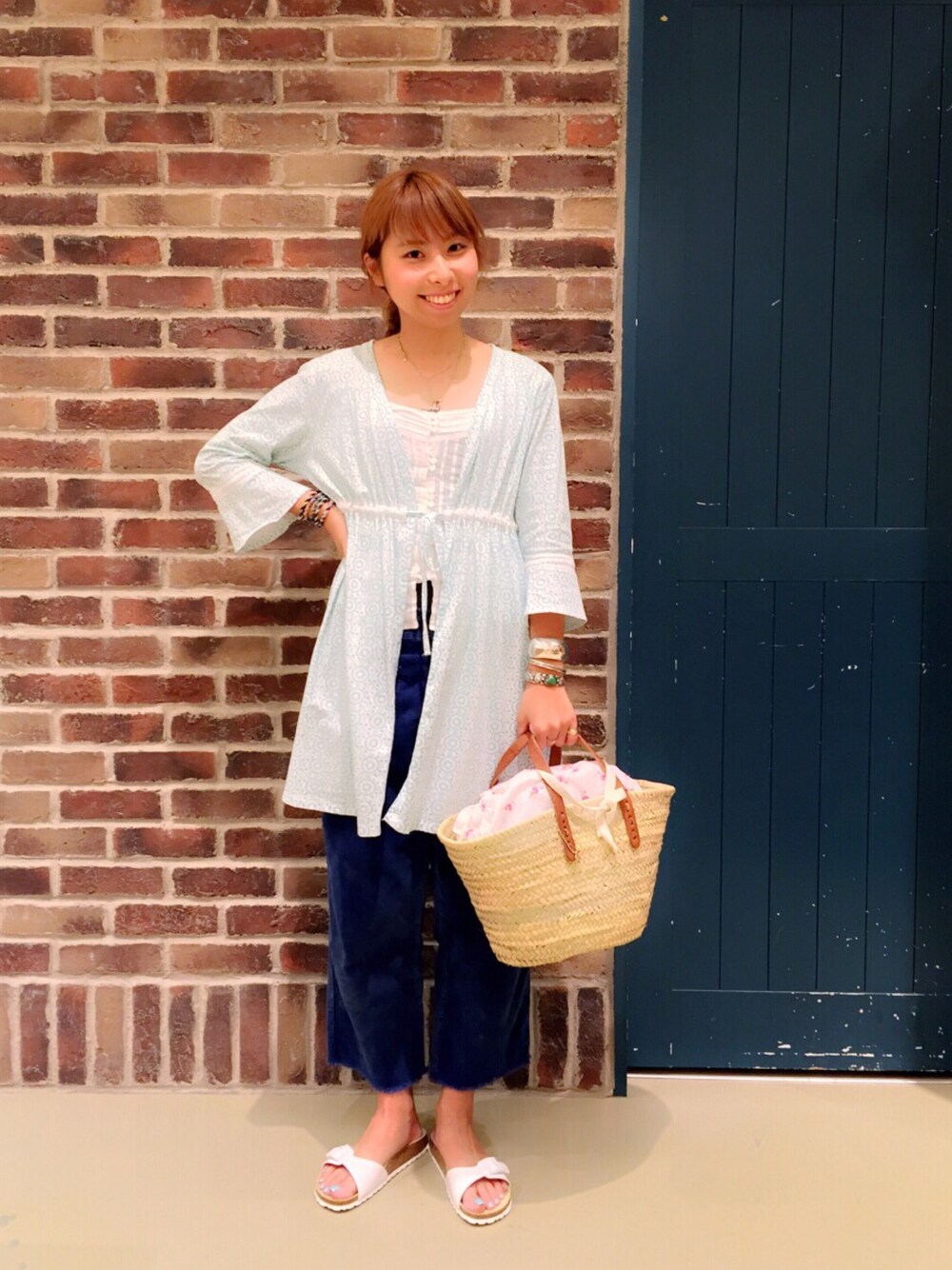 ブルー系のその他パンツ、ホワイト系のかごバッグ、ホワイト系のサンダルを着用したレディースの春コーディネートの1枚目の写真