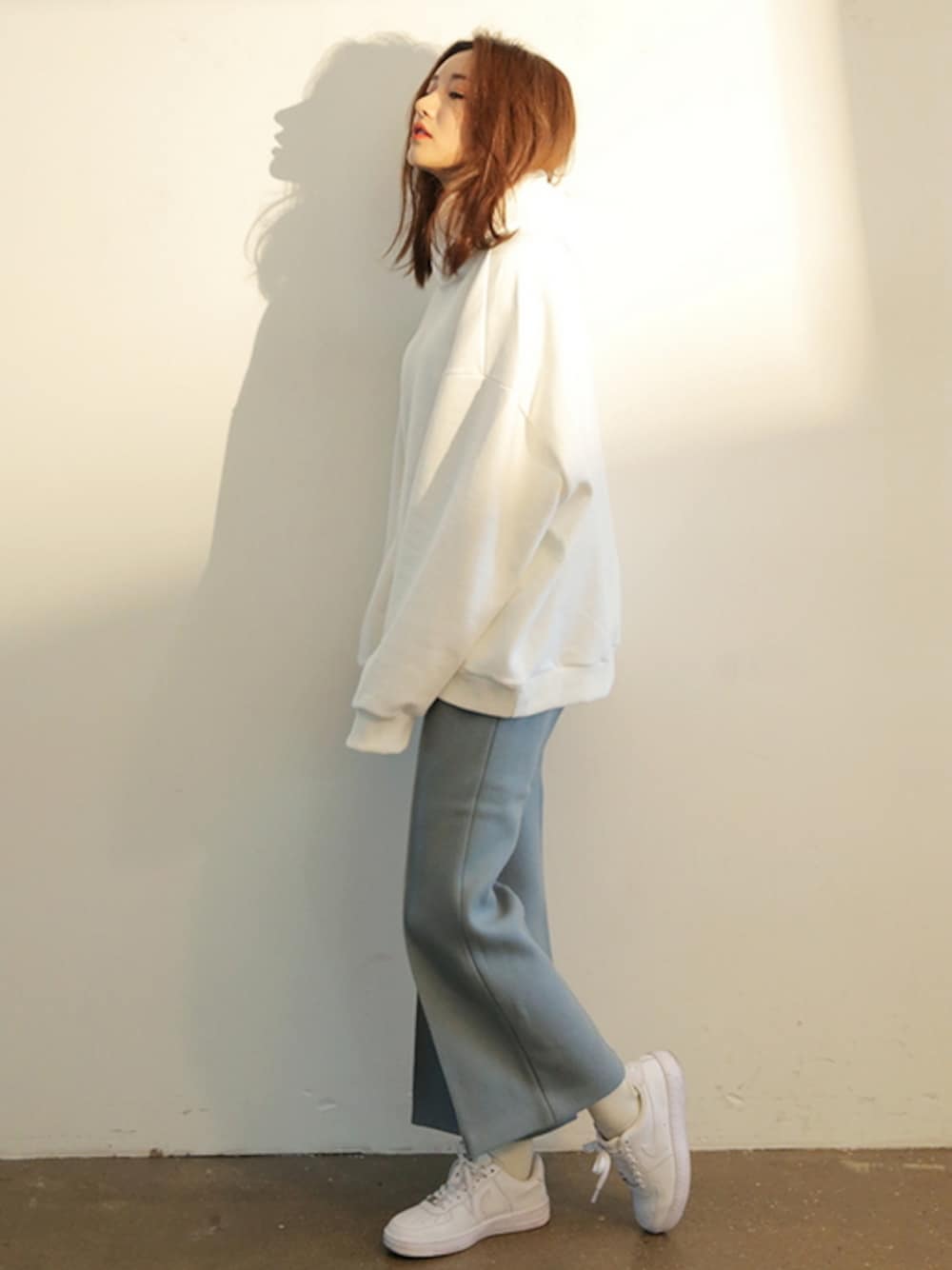 ホワイト系のパーカー、グリーン系のスラックスを着用したレディースの冬コーディネートの1枚目の写真