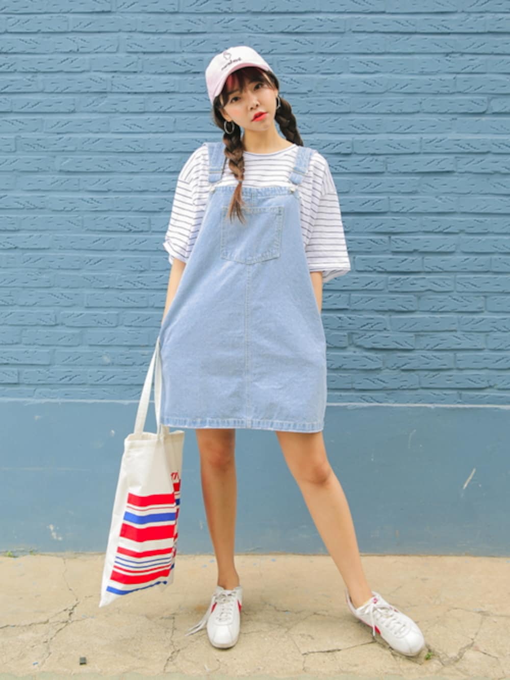 「トートバッグ、 Stylenanda、 スニーカー、 キャップ、 ボーダー、 デニムスカート、 ジャンパースカート、 きれいめカジュアル、 女の子、 キレイめ」｜「ウォッシングデニムジャンパースカート（デニムスカート、ブルー系）」を使った、STYLENANDAさん（レディース・164cm）の春コーディネートの1枚目の写真