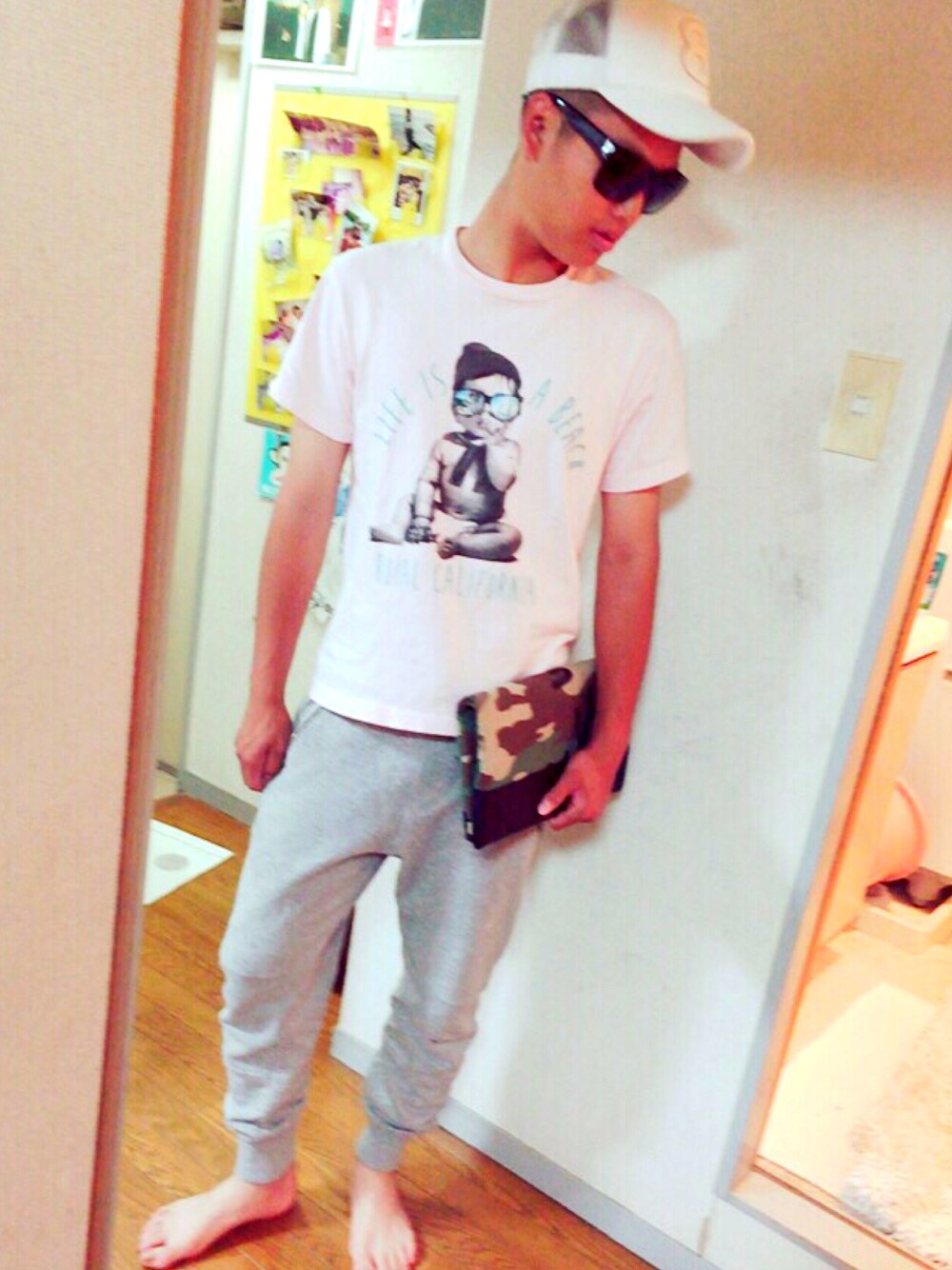 ピンク系のTシャツ/カットソー、グレー系のスラックス、その他のクラッチバッグを着用したメンズの夏コーディネートの1枚目の写真