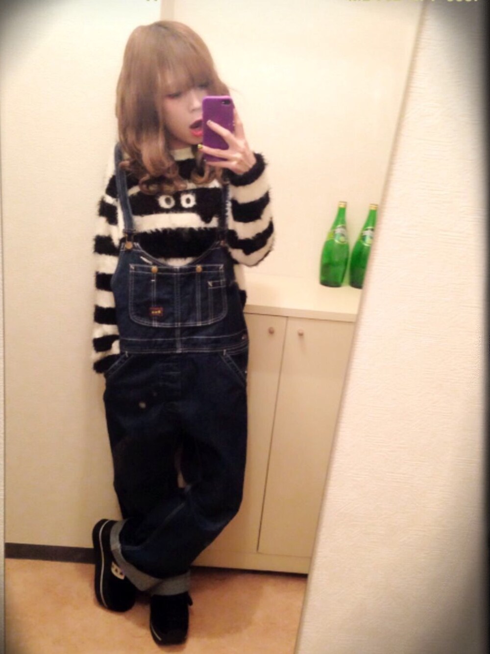 ブルー系のサロペット/オーバーオール、ホワイト系のニット/セーター、ブラック系のスニーカーを着用したレディースの春コーディネートの1枚目の写真